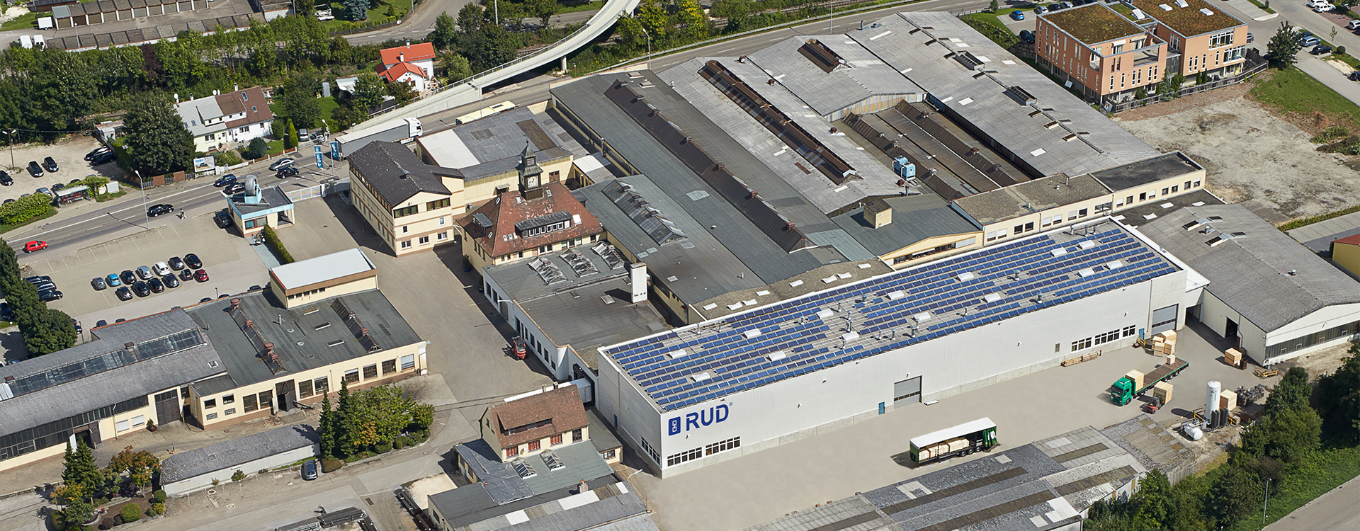 Luftaufnahme des RUD Firmengebäudes mit umliegenden Straßen, Hallen und Wohnhäusern in einer städtischen Umgebung.